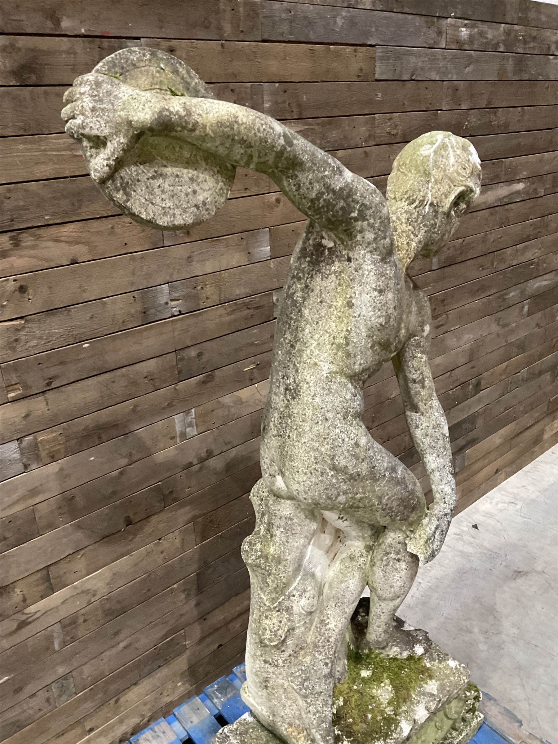 Life-size weathered cast stone Greek Discus Athlete, seated on rectangular slab raised on associated architectural plinth
