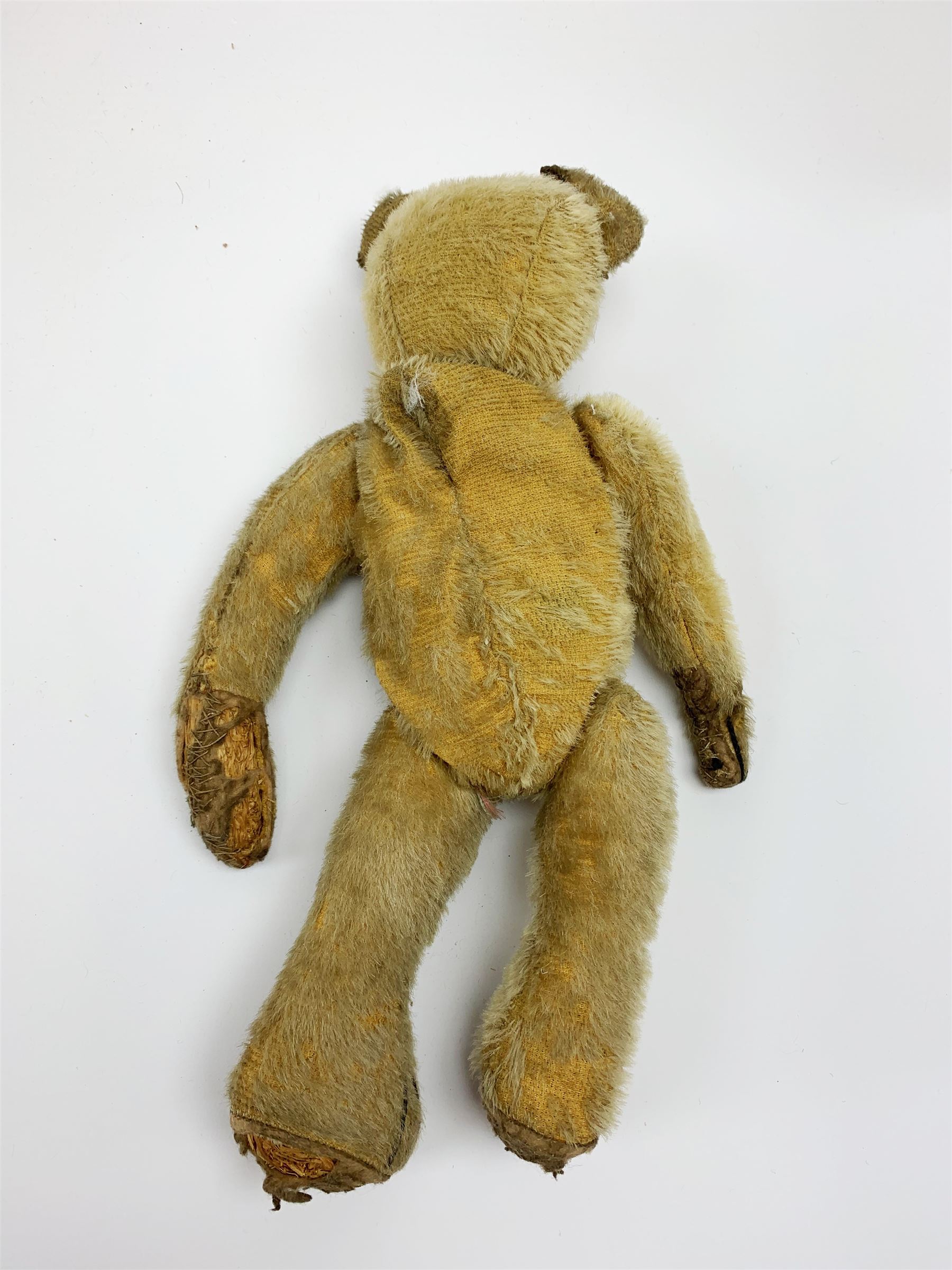 Early 20th century American mohair teddy bear c1920 with wood wool filled body humped back body with jointed limbs, black boot button eyes and horizontal stitched nose and mouth H12