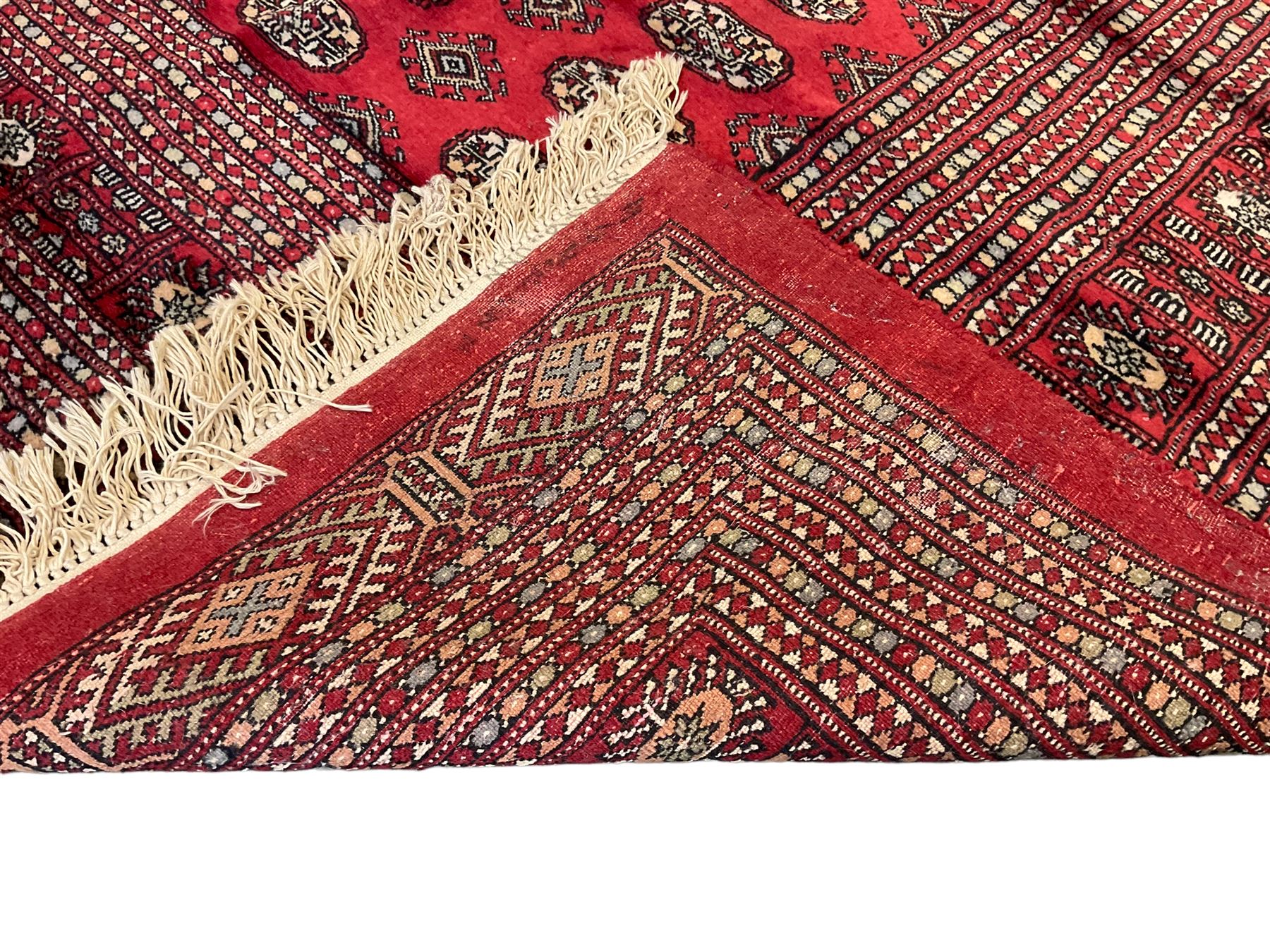 Persian Bokhara crimson ground carpet, the field decorated with repeating Gul motifs and lozenges, the multi-band geometric border with stylised plant motifs, two additional bands at the ends with geometric lozenges