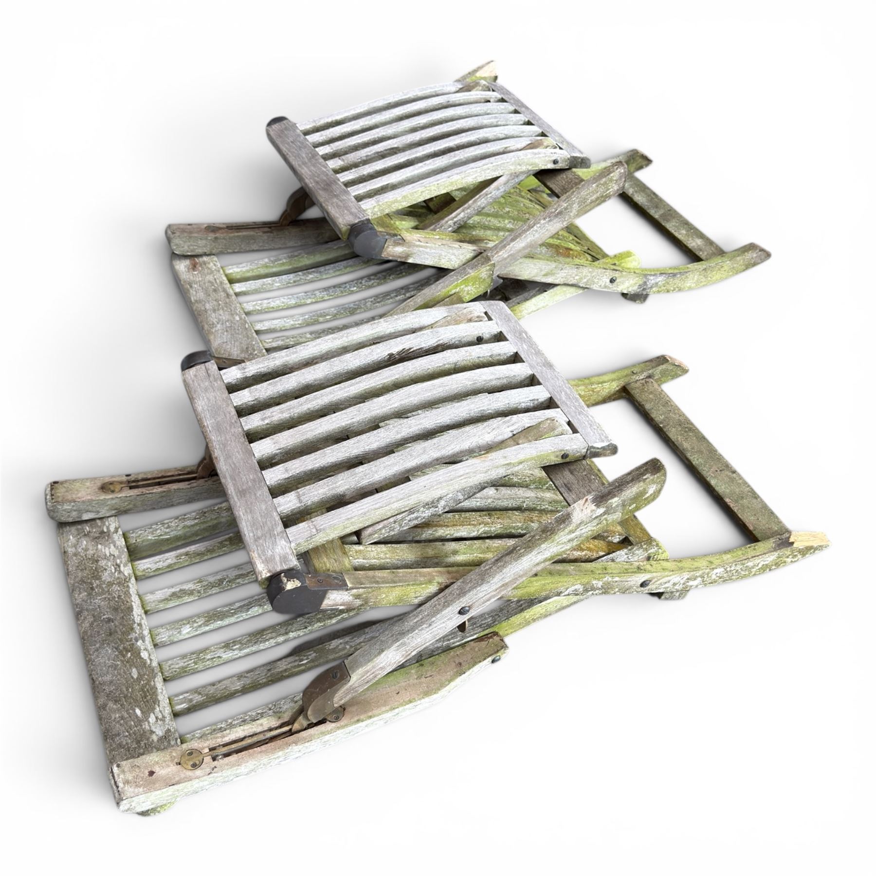 Pair of teak reclining garden steamer armchairs, each with an adjustable slatted back, curved slatted seat and footstool