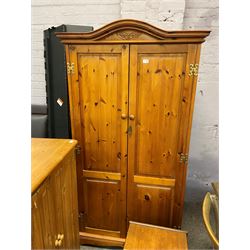 Stained pine double wardrobe, raised and projecting cornice, two panelled doors enclosing hanging rail, raised on shaped plinth support 
