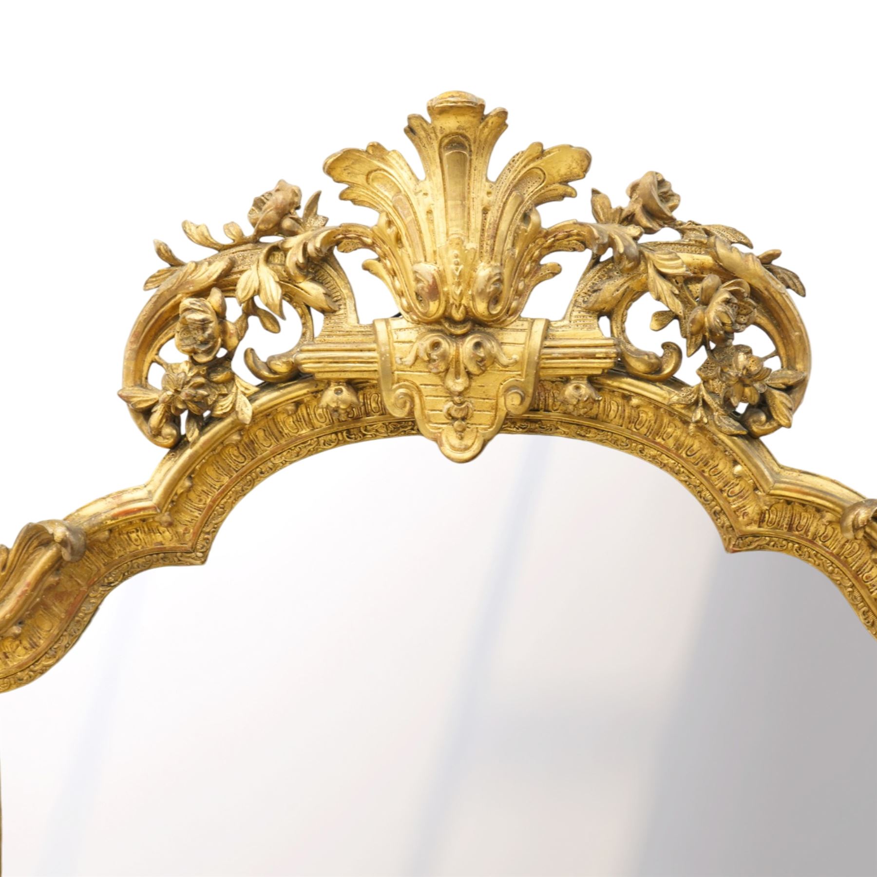 Victorian giltwood and gesso framed ornate wall mirror, the protruding cartouche pediment decorated with extending scrolls of acanthi and flower heads, with scrolled foliage corners flanking a carved slip with further gadrooned scroll decoration, contained a shaped rectangular bevelled plate, over a pierced and scrolling scallop shell terminal