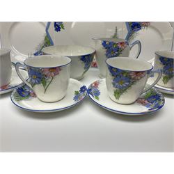 Shelley Strand shaped tea wares, decorated with blue and pink daisies upon a white ground, comprising four teacups, four saucers, three tea plates, milk jug, sugar bowl and cake plate, all with printed green mark beneath and painted pattern no 12216