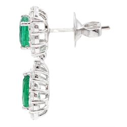 Pair of 18ct white gold emerald and diamond pendant earrings, each stud set with a cushion cut emerald and round brilliant cut diamond surround, suspending a further pear cut emerald and diamond cluster stamped, total emerald weight approx 3.45 carat, total diamond weight approx 1.70 carat