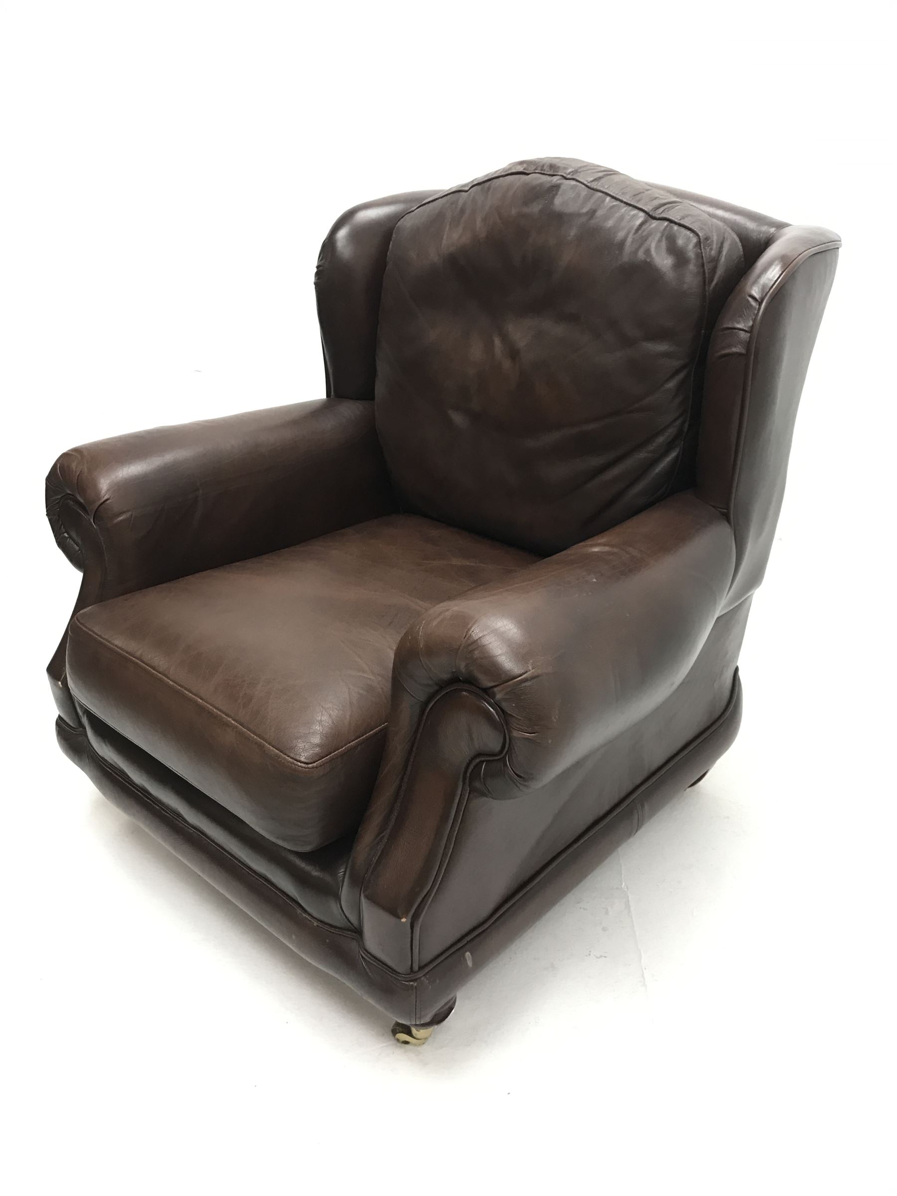 Thomas Lloyd wing back armchair upholstered in a brown leather, turned supports on castors