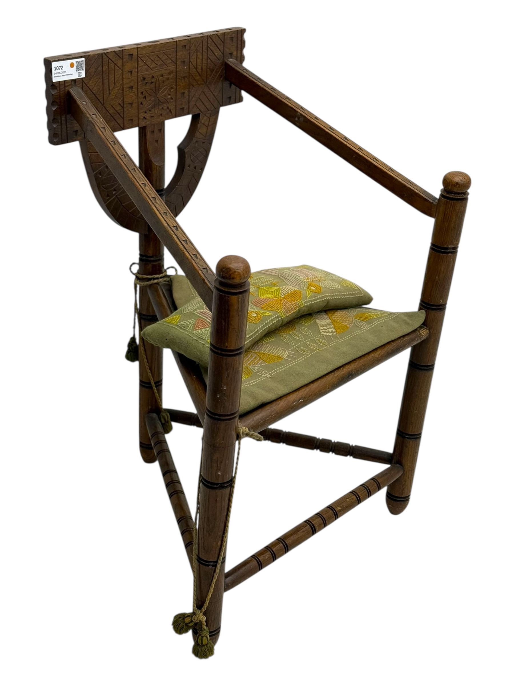 19th century swedish monk's chair, the oak frame with triangular seat and sloped arms, the backrest carved with geometric chipwork and a central pierced medallion 