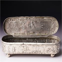19th century continental silver box of oval design , the hinged cover with swing handle embossed with sailing ships, castle etc, the base decorated with horse and cart in rural landscape and the sides with a hunting scene on ball feet L15cm