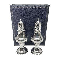 Silver plated two piece cruet set, comprising salt shaker and pepper shaker, both of waisted form with engraved rope twist borders, the removable pierced covers each with engraved lattice decoration, upon a circular spreading foot, H13.3cm, contained within velvet lined fitted case