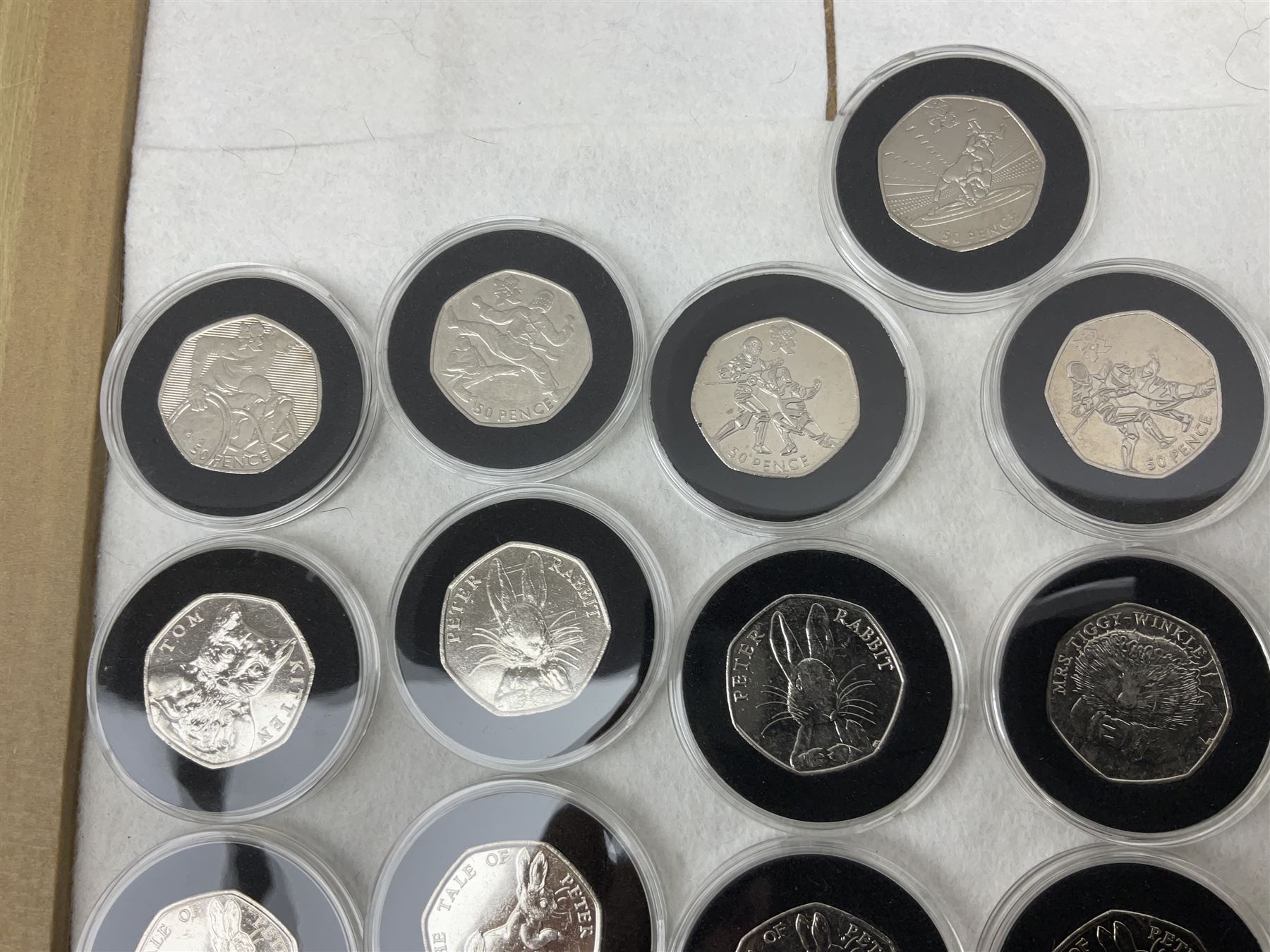 Thirty-seven commemorative fifty pence coins, including 2011 wrestling, other Olympics, Beatrix Potter etc, housed in capsules