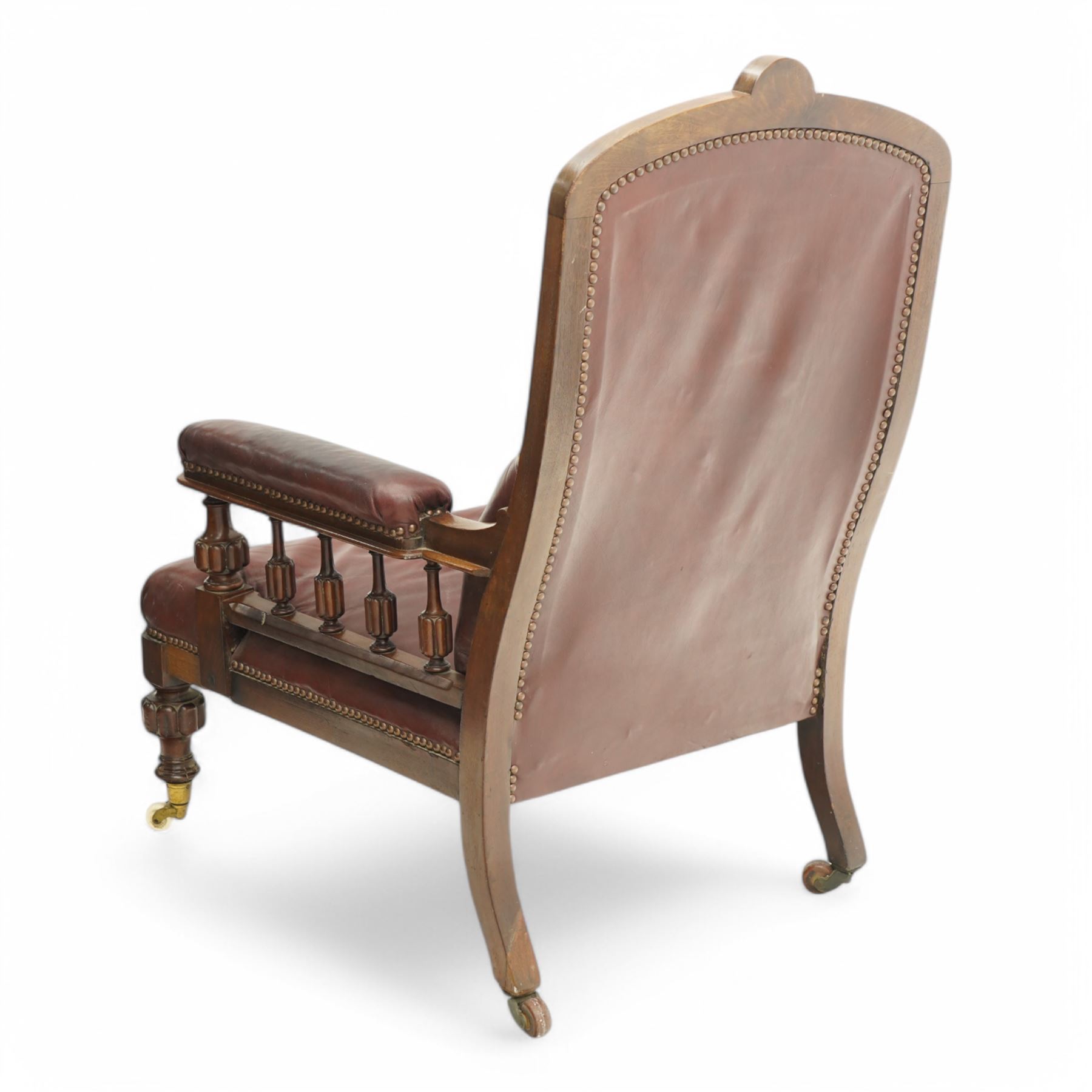 Late Victorian mahogany open armchair, arched cresting rail decorated with turned roundel, upholstered in buttoned burgundy leather, the upholstered arms on turned and lobe carved balustrade, turned and lobe carved front feet with brass and ceramic castors 