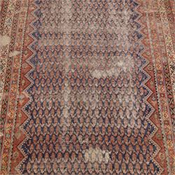 West Persian Kurdish vintage carpet, indigo field decorated with an all-over repeating boteh design arranged in diagonal rows framed by angular spandrels and enclosed by multiple geometric borders in a palette of indigo blue, madder red, soft green and ivory