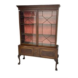19th century mahogany bookcase display cabinet on stand, dentil cornice over blind fretwork frieze, fitted with two astragal glazed doors enclosing two shelves, above two cupboards with re-entrant panelled facias flanking blind-fretwork panel in stylised plant motif form, raised cabriole supports with ball and claw feet