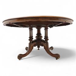 Victorian inlaid burr-walnut and marquetry oval centre table, quarter veneered tilt-top with scrolling foliate and floral marquetry reserves on a turned carved column with clustered supports raised on four out-swept scroll legs on ceramic castors  