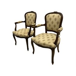 Pair French style beech framed open armchairs, the cresting rails carved with flower heads, upholstered in floral patterned fabric, on cabriole supports