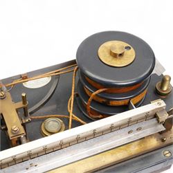 Lord Kelvins Patent electric current balance, no. 823, by Kelvin & James White Ltd Glasgow & London, with two pairs of horizontally mounted coils, suspended beam balance mounted on an ebonite base under glass and brass cover, with box of weights and accessories, raised on three wooden supports, W51cm H37.5cm