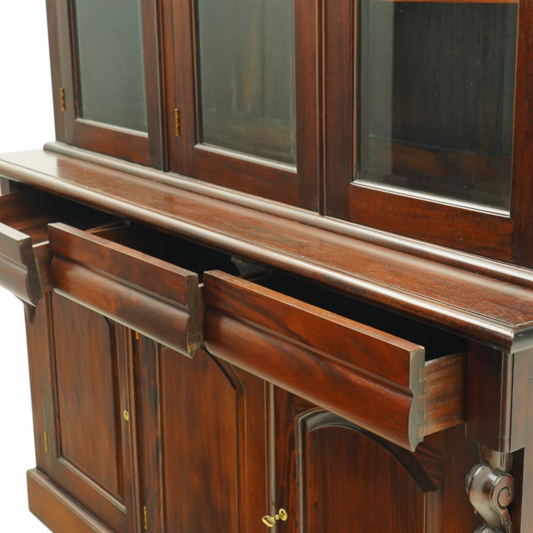 Victorian revival hardwood dresser, projecting moulded cornice above three glazed doors enclosing shelves, moulded top over three drawers and three panelled cupboard doors, flanked by applied carved scroll brackets, on plinth base,