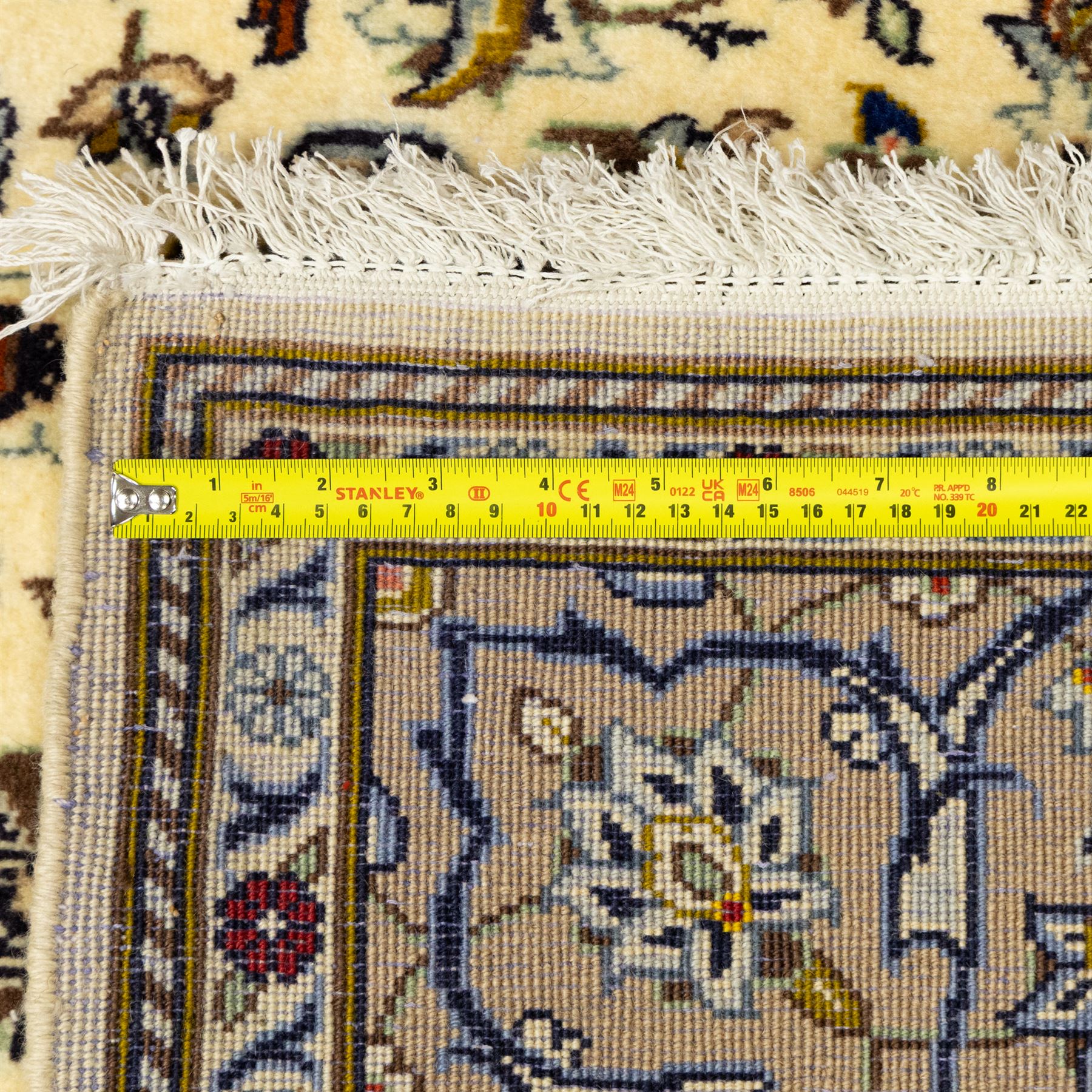 Central Persian Kashan hand-knotted rug, ivory ground, with a central shaped floral medallion with pendants, surrounded by scrolling foliate and floral motifs incorporating rosettes, palmettes and delicate vine work, enclosed by a beige border with repeating palmettes and meandering vines, flanked by narrow floral guard stripes, with cotton fringes