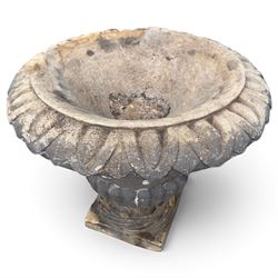 Set of three 19th century weathered carved sandstone garden urns of Neoclassical campana form, the broad everted rim carved with pointed egg-and-dart motifs, above a plain waisted bowl with gadrooned underbelly, on moulded rope-twist socle and square plinth base