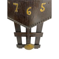 1920’s Art deco drop dial wall clock - with an eight day spring driven timepiece movement, hexagon dial in dark oak with applied brass Arabic numerals and arrow shaped hands, open framework backboard, visible wooden pendulum with a brass faced bob.