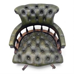 Mid 20th century buttoned green leather office chair, the curved back and arms over a circular frame with turned spindle supports, on a revolving base with four splayed legs and brass castors