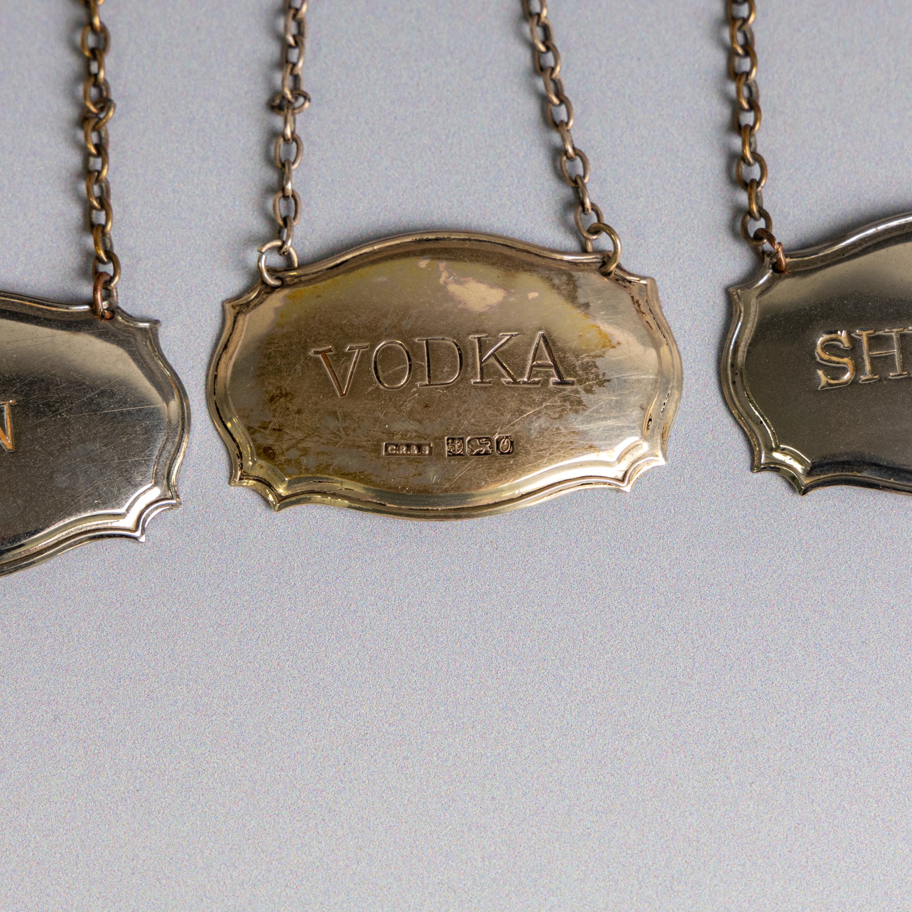 Five silver decanter labels, of varying design, including Bacardi, Vodka, Rum, Brandy and Whisky, all hallmarked together with two silver plated Gin and Sherry examples