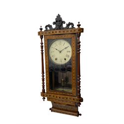 A late 19th century spring driven American Eight-day wall clock, striking the hours on a bell, in a parquetry case with contrasting oak, maple, walnut, and other hardwoods, with a flat top, carved cresting and finials rectangular glazed door flanked by finely turned pilasters, with a painted dial with roman numerals and minute track, steel spade hands and faux mercury pendulum reflected in a rear case mirror.   


