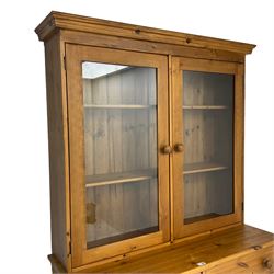Large pine bookcase on cupboard, the upper section enclosed by two glazed door, the lower section fitted with two drawers and double cupboard, on plinth base