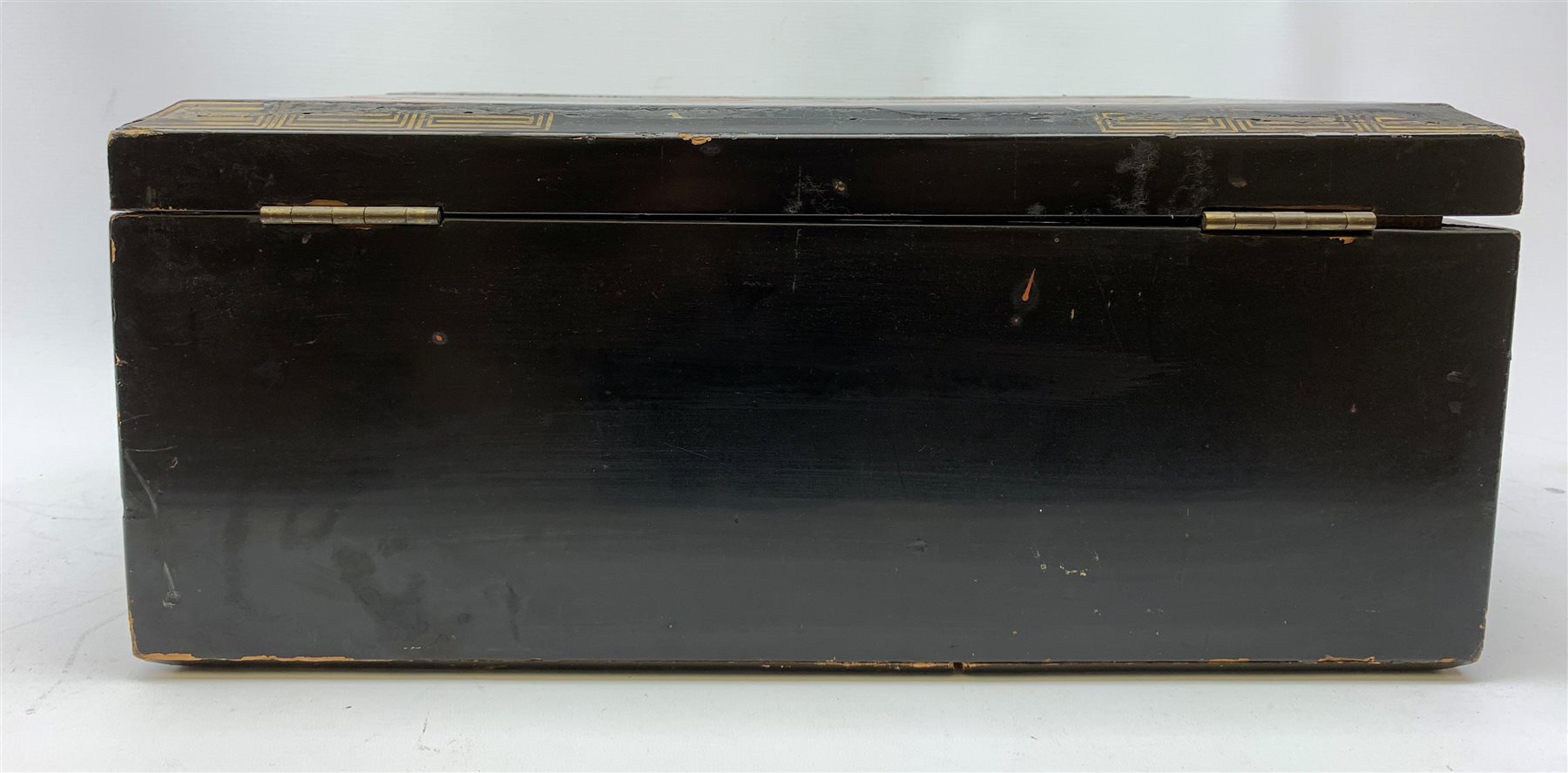  A 20th century Chinese black lacquer and gilt detailed writing box, decorated with figures, pagodas and cranes amidst a mountainous landscape, the hinged cover opening to reveal a compartmented interior and fold out baize lined slope, H20cm L46.5cm D31.5cm.   