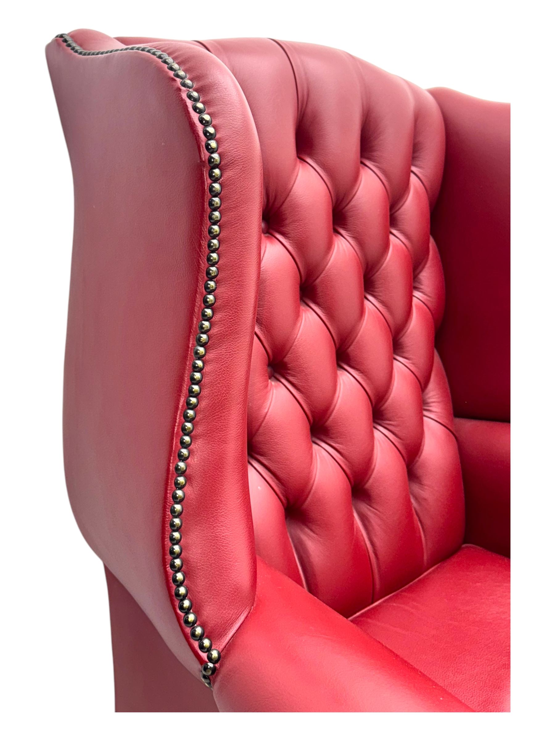 Kingsgate - contemporary 'Suffolk' wingback armchair and matching stool, upholstered in red leather with deep button tufting and brass stud trim, raised on square section supports 