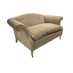 Traditional two seat sofa, curved back over scrolled arms, upholstered in crushed beige fabric with matching loose cushions, on turned front supports with brass and ceramic castors