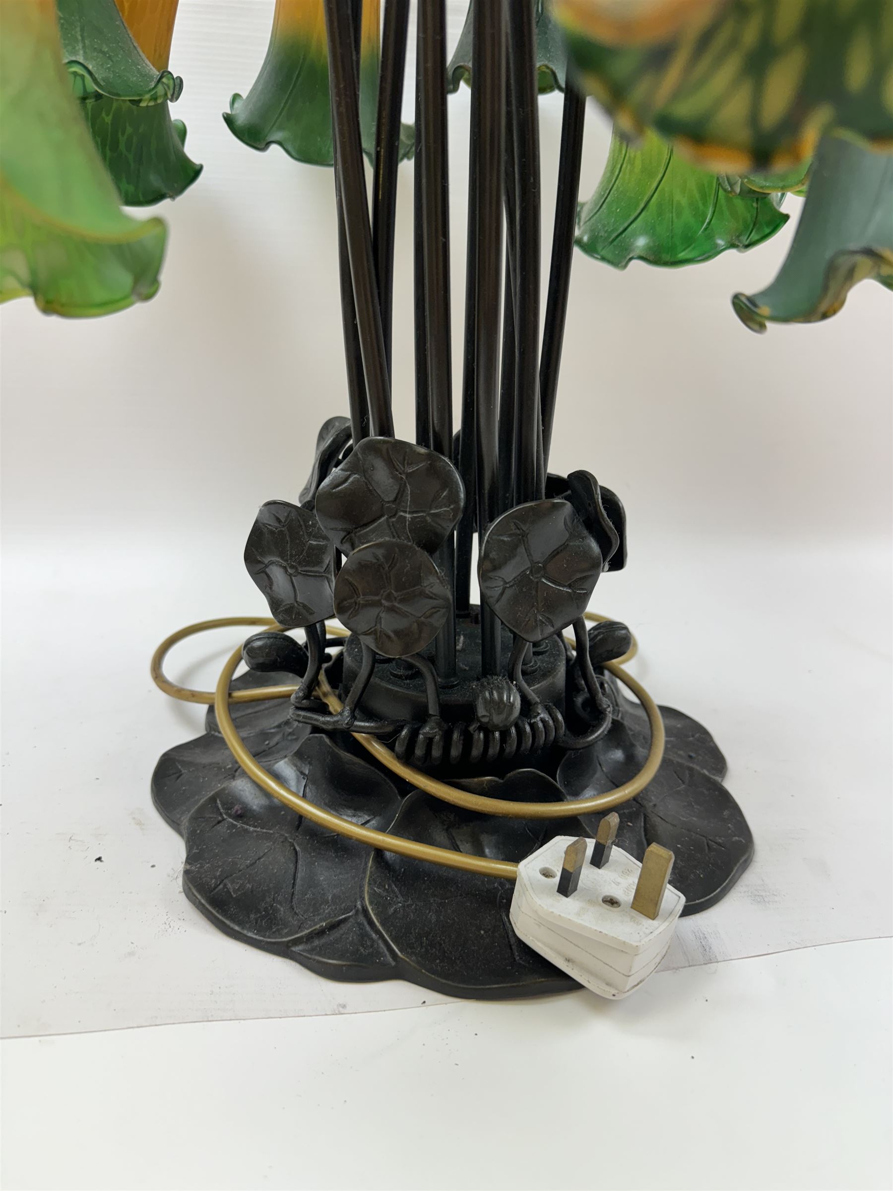 Art Nouveau Tiffany style table lamp, the bronzed base modelled as lily pads leading to tendrils and twelve branches supporting green and yellow glass lily flower shades, H53cm