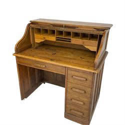 Early 20th century oak roll-top desk, the tambour enclosing pigeon holes and small drawers, the base fitted with slide, a single long drawer and three smaller drawers
