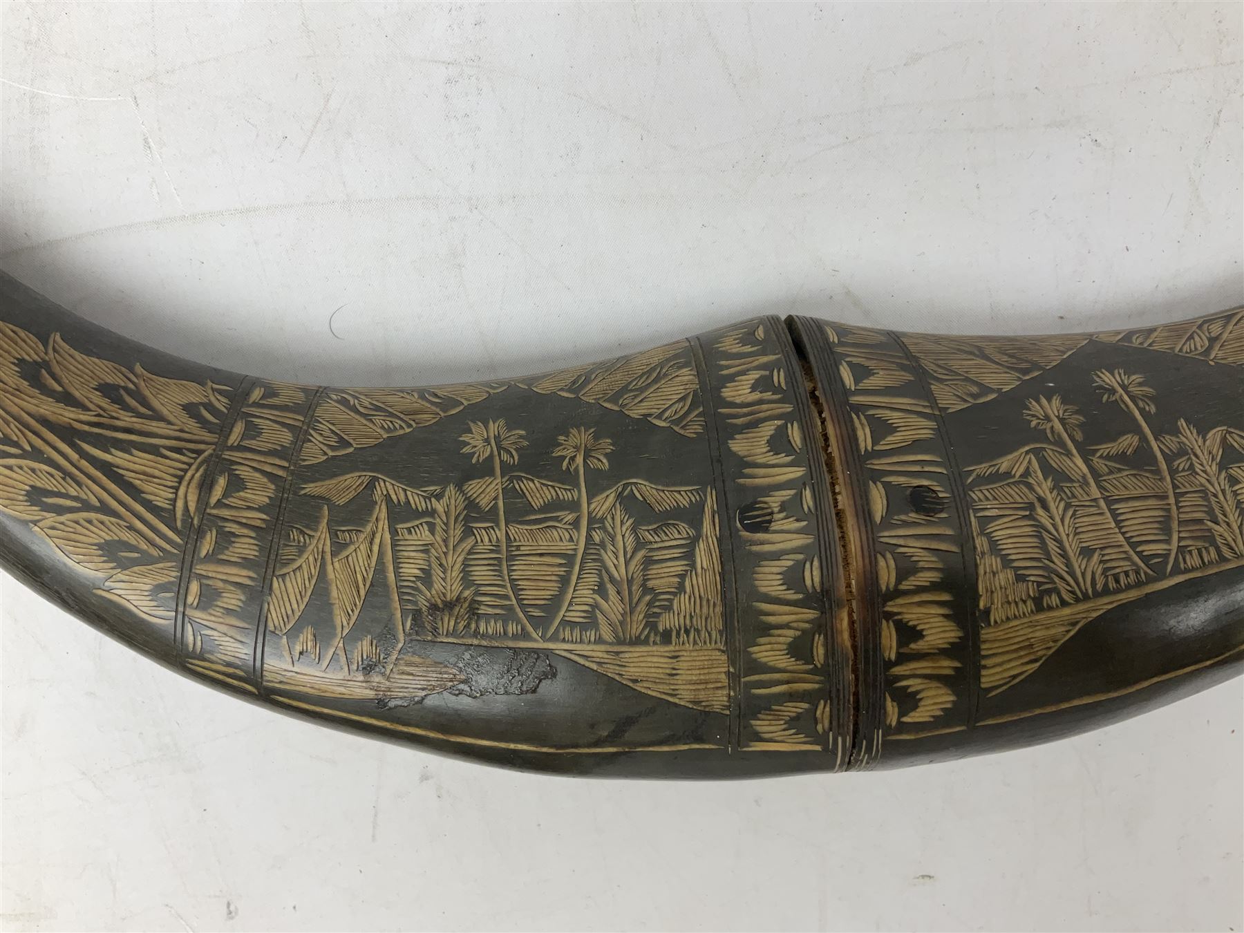 Carved water buffalo horn wall pocket, engraved with landscape scene with patterned borders with pierced foliate panel, together with a pair of horns with similar engraved decoration, L47cm