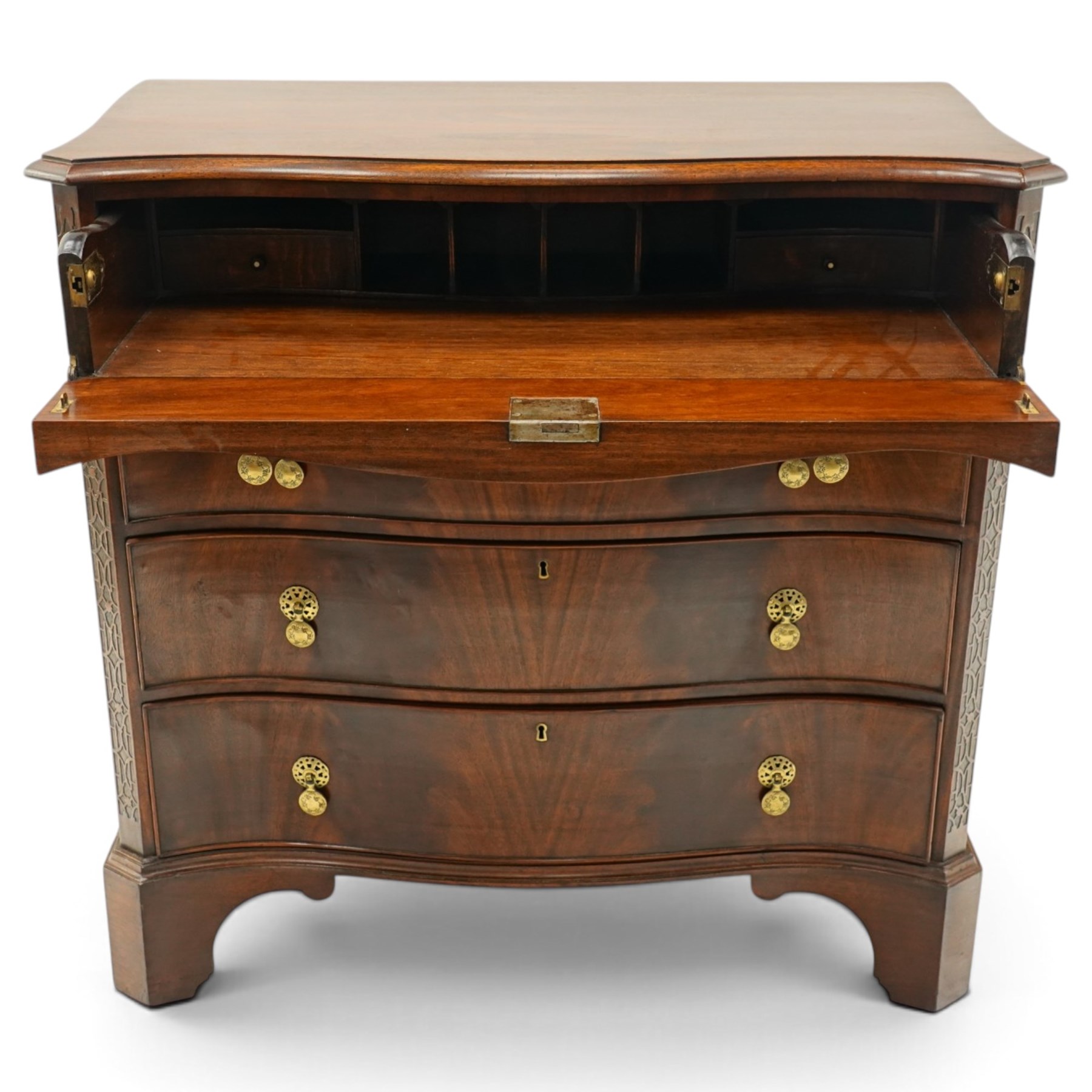 Quality Georgian design mahogany serpentine secretaire chest, the shaped top with moulded edge, fitted with cock-beaded secretaire drawer with button-release fall-front enclosing fitted interior, over three graduating drawers with brass drop handles on pierced circular plates, the canted uprights carved with blind-fret strapwork, lower moulded edge on shaped bracket feet