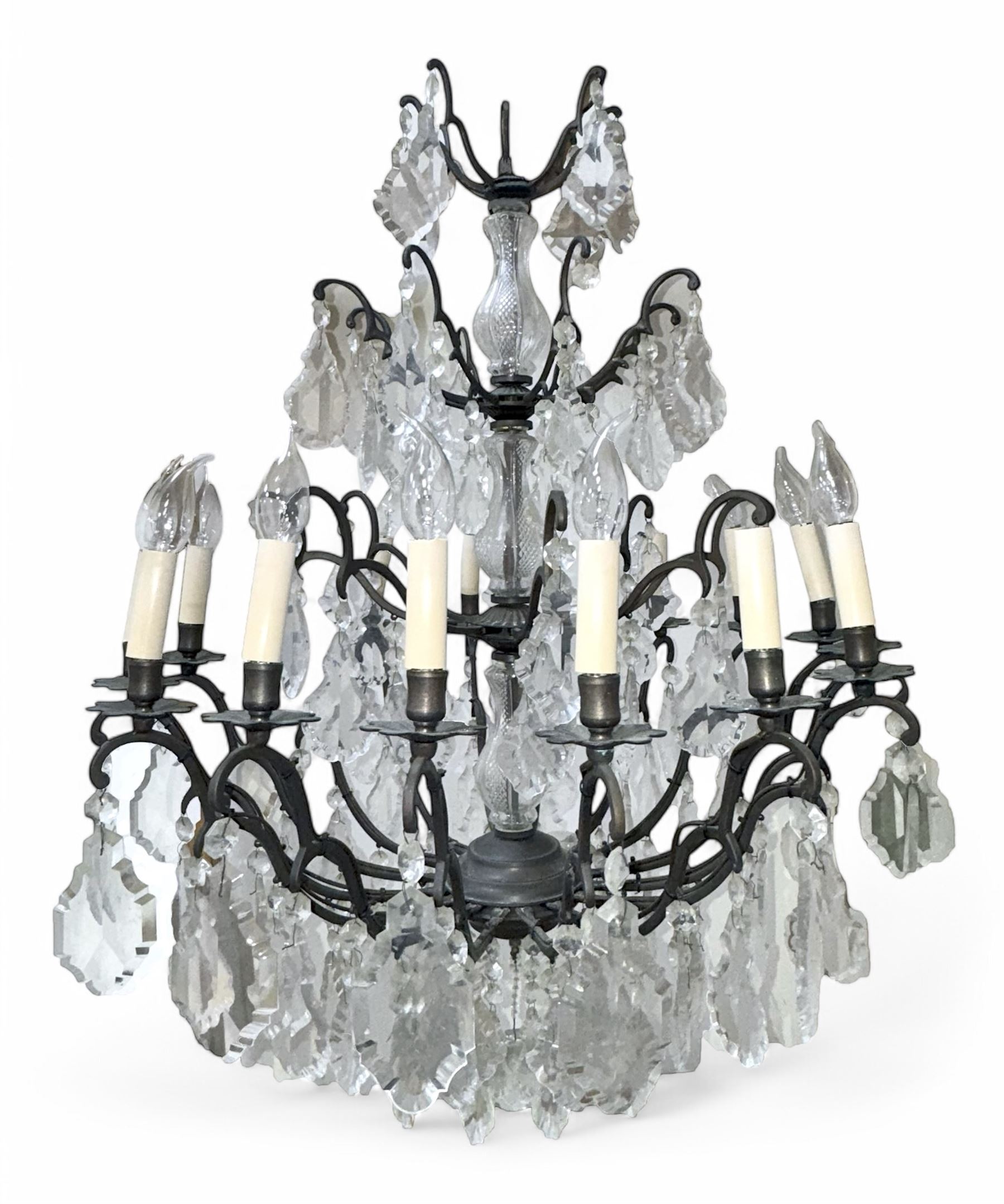 Early 20th century continental cut glass and metal chandelier, with sixteen candle style lights on a single tier of scrolled arms, hung with faceted glass drops and centred by a mould-blown and cut glass baluster stem, suspended from a ceiling rose and chain