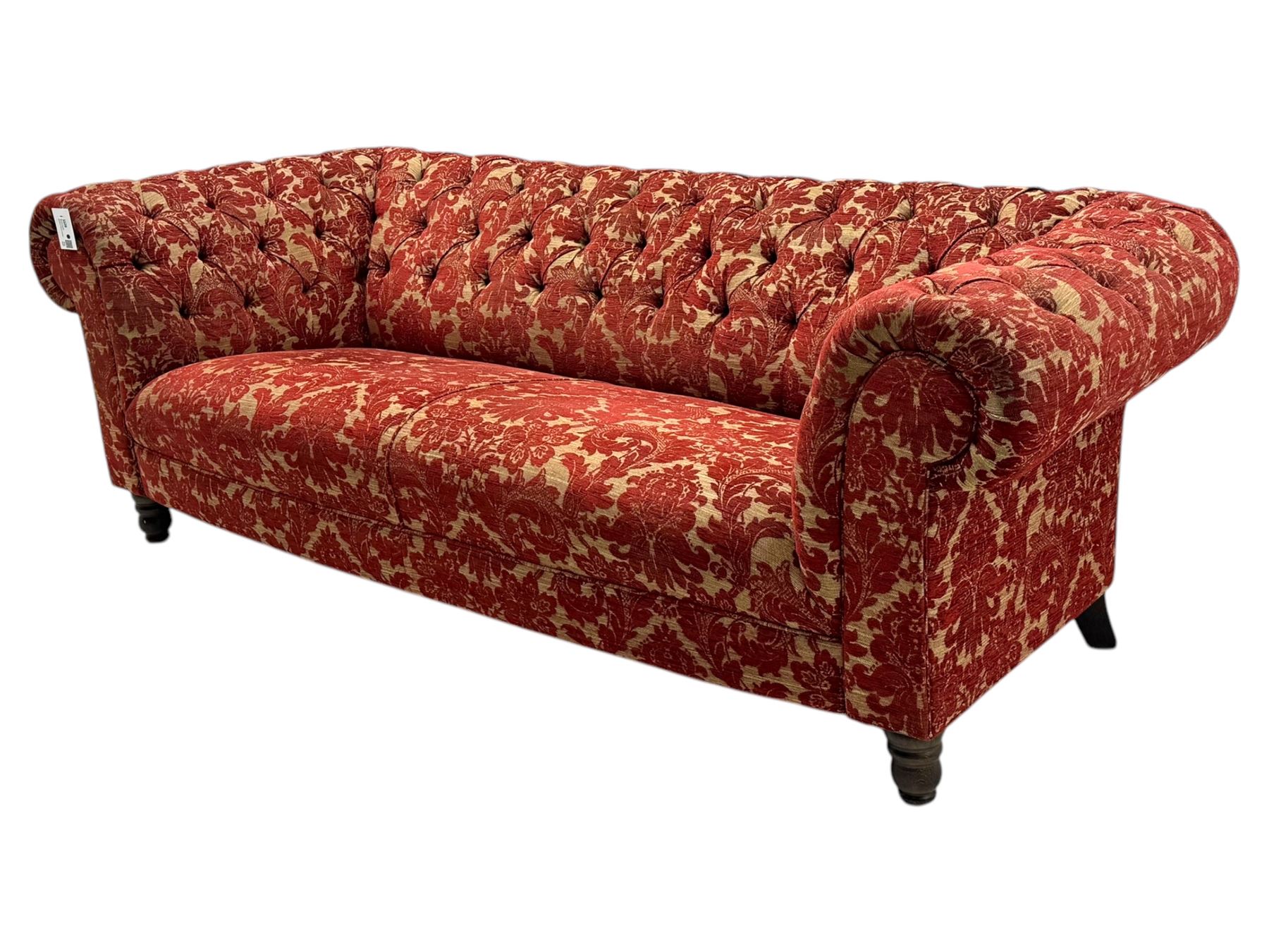 Late 20th century upholstered Chesterfield sofa, in red damask floral fabric, with deep buttoned back and arms, scrolled arms at equal height to back, on turned front supports