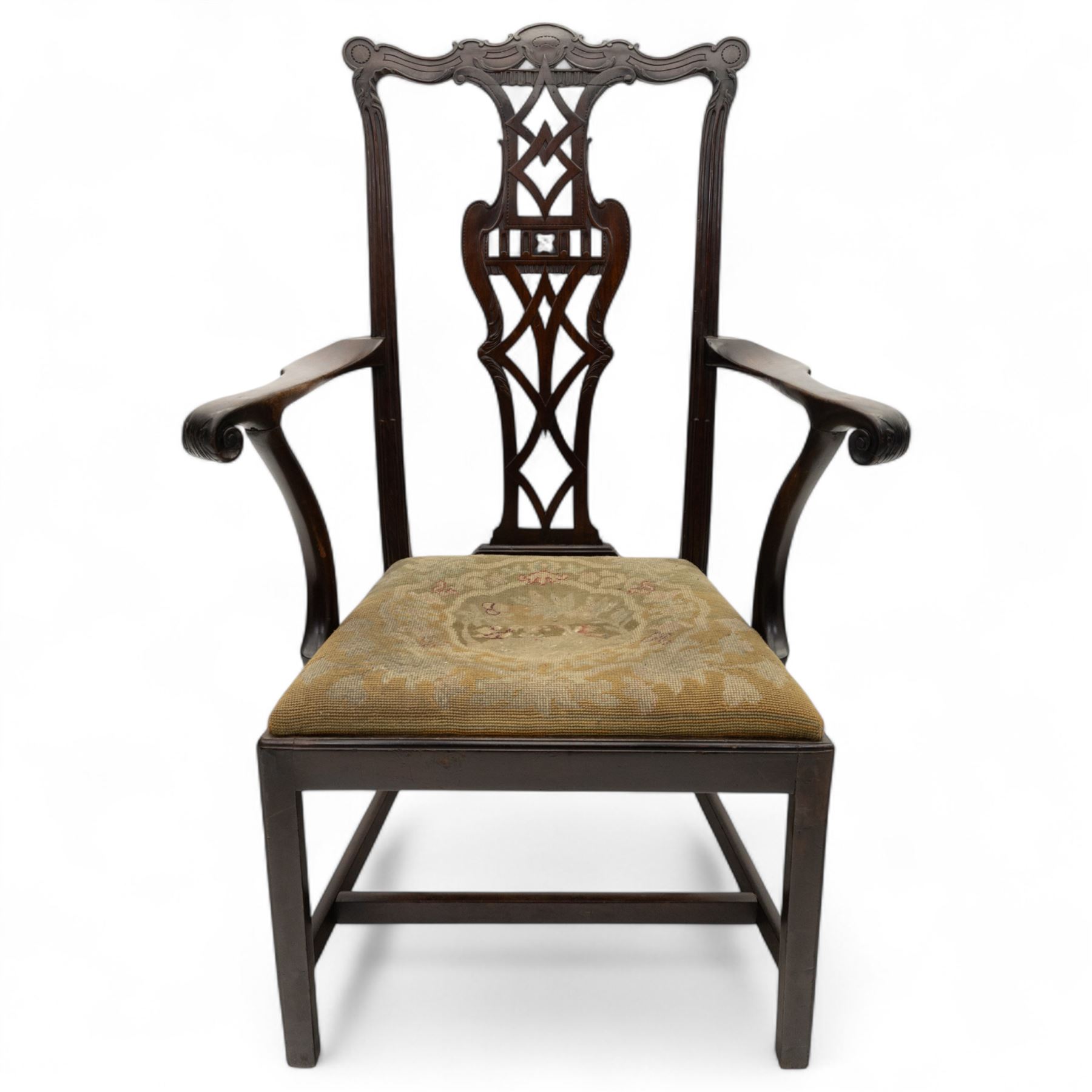 19th-century Chippendale Revival design mahogany oversized high-back armchair, serpentine crest carved top rail above pierced back splat with interlaced ribbon carving and geometric fretwork design, and outward scrolling arms above drop-in needlework seat on square chamfered legs 