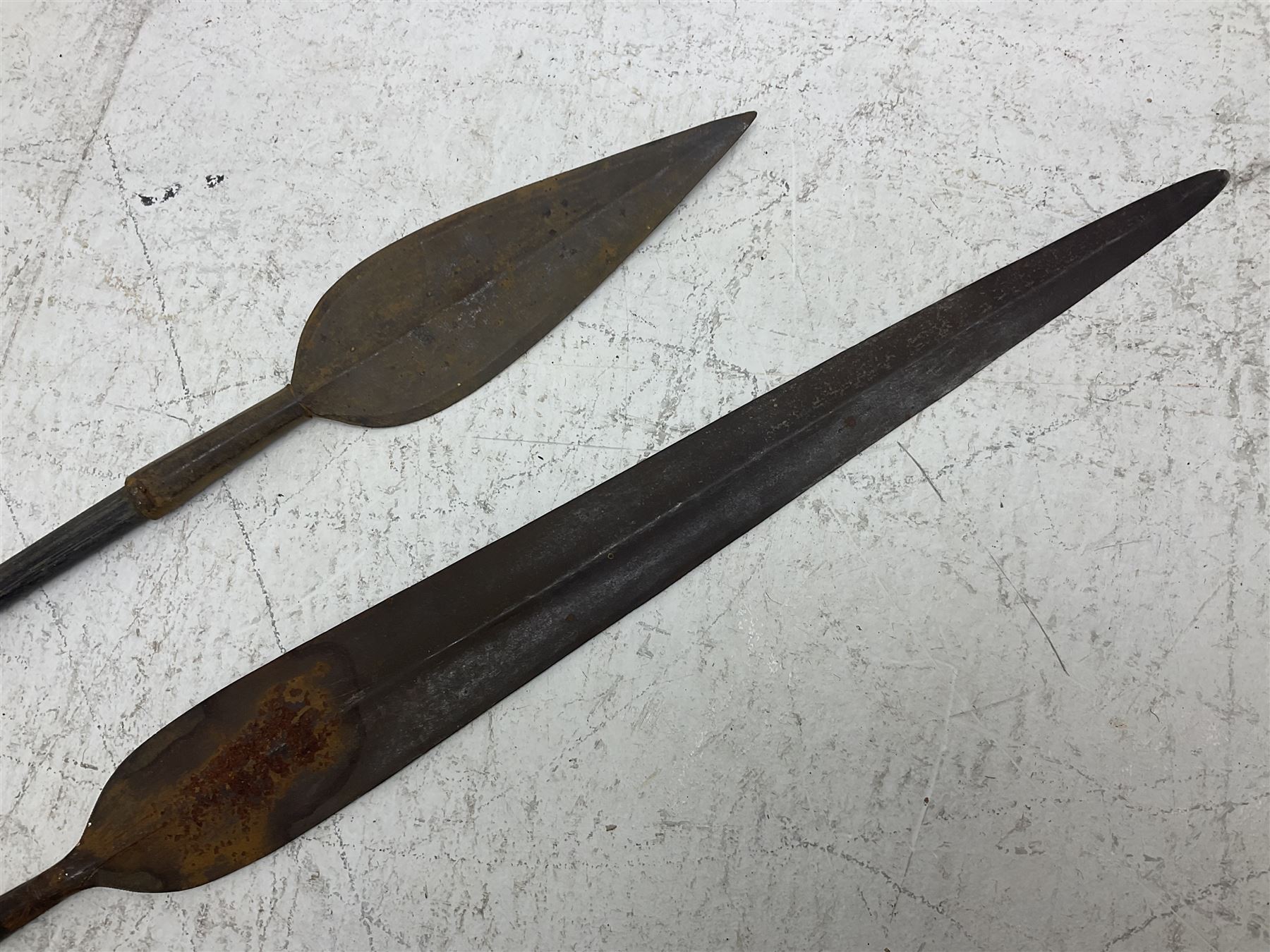 Native long-shafted spear, the large iron head with central medial ridge and decorative neck, on plain circular haft L260cm; and another similar Native long-shafted spear with cane haft L249cm (2)