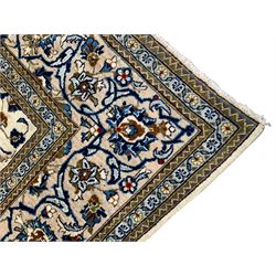 Persian Kashan ivory ground rug, the field decorated with stylised plant motifs and interlacing leafy branches, scrolling border decorated with further plant motifs, floral design guard bands  