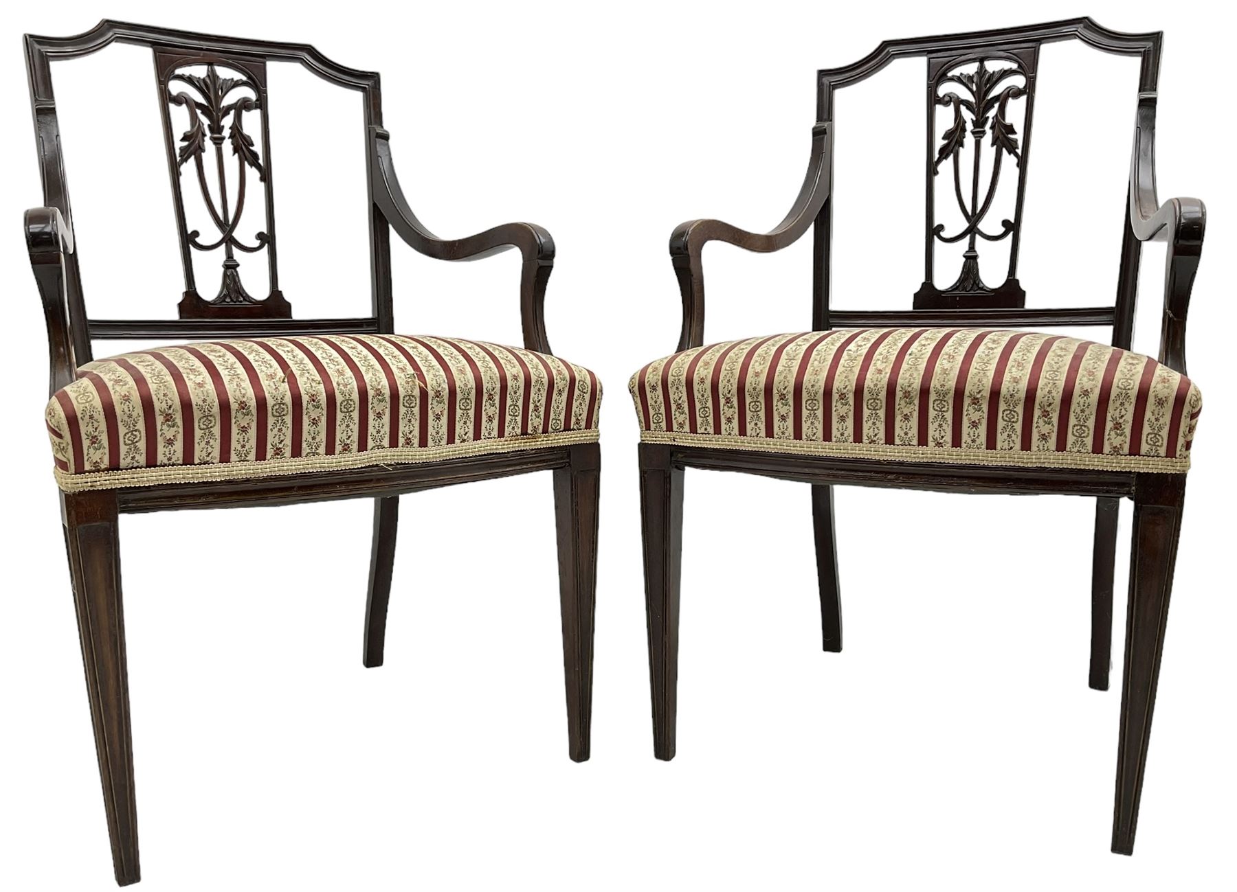 Edwardian mahogany framed three-piece salon suite - two-seat sofa, stepped cresting rail over acanthus and scroll carved pierced splat, upholstered in striped fabric (W124cm, H87cm, D62cm); and a pair of matching armchairs (W60cm) 