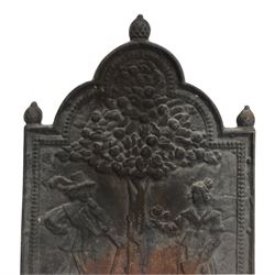 Cast iron fire back, depicting a couple under a tree with three acorn finials, H74cm