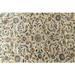 Central Persian Kashan hand-knotted rug, ivory field intricately decorated with an all-over design of scrolling vines, palmettes, and stylized lotus motifs in shades of soft blue, pale gold, and indigo within floral borders