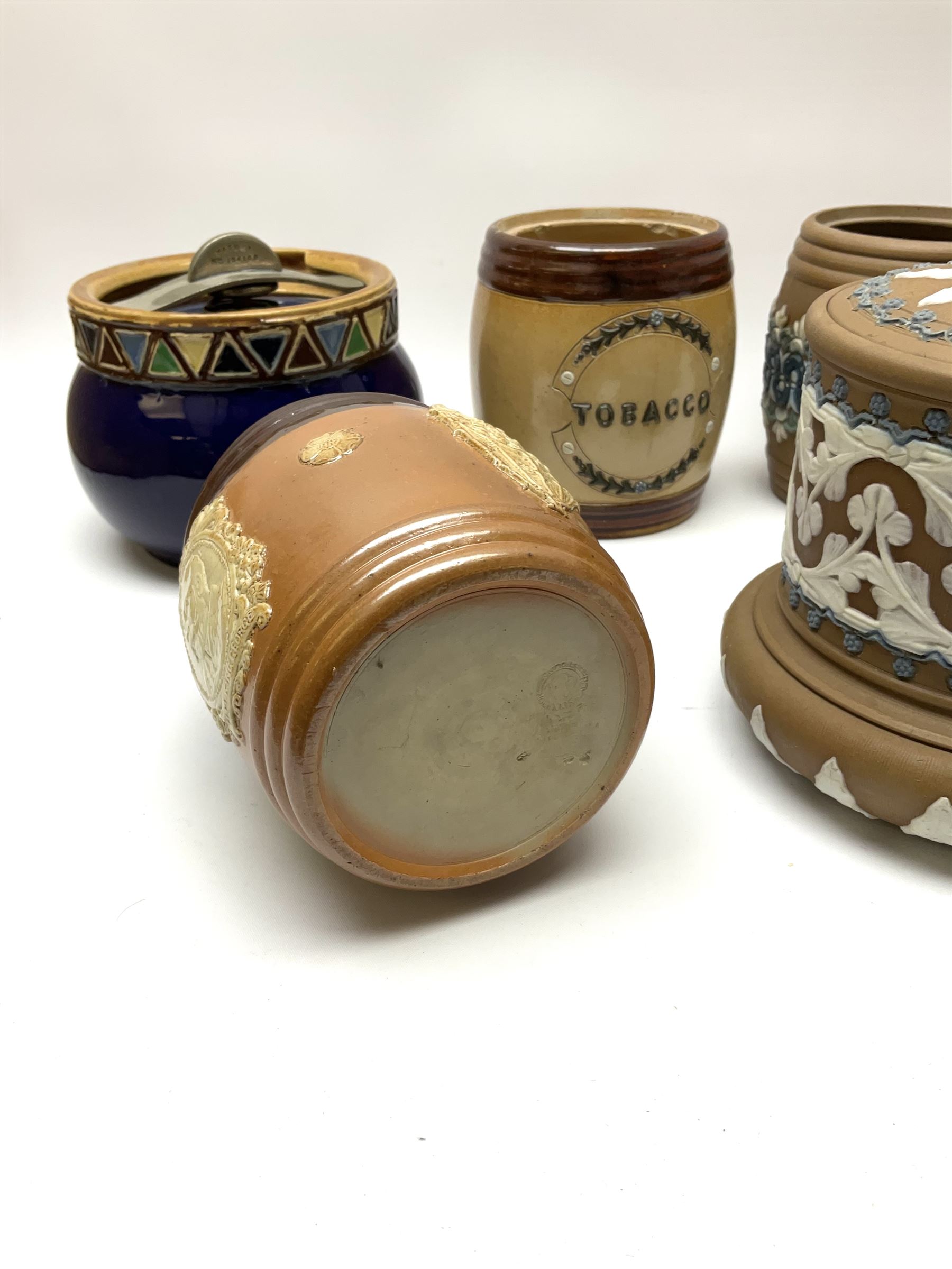 A group of Doulton Lambeth and Royal Doulton tobacco jars, most with relief moulded foliate decoration, (four examples lacking covers), largest example H15cm. 
