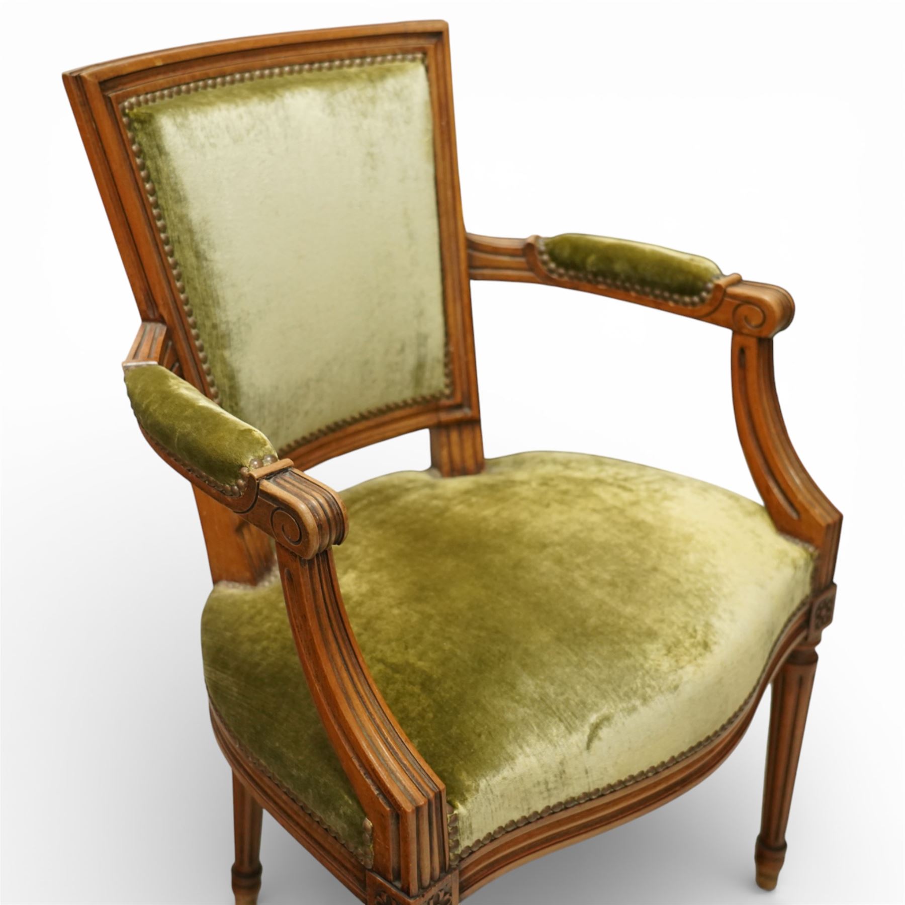 French Louis XVI style walnut armchairs, rectangular upholstered backs with nailhead trim, padded seats upholstered en suite, out-swept arms with upholstered pads, fluted supports with carved rosettes to the knees, on turned and fluted tapering legs