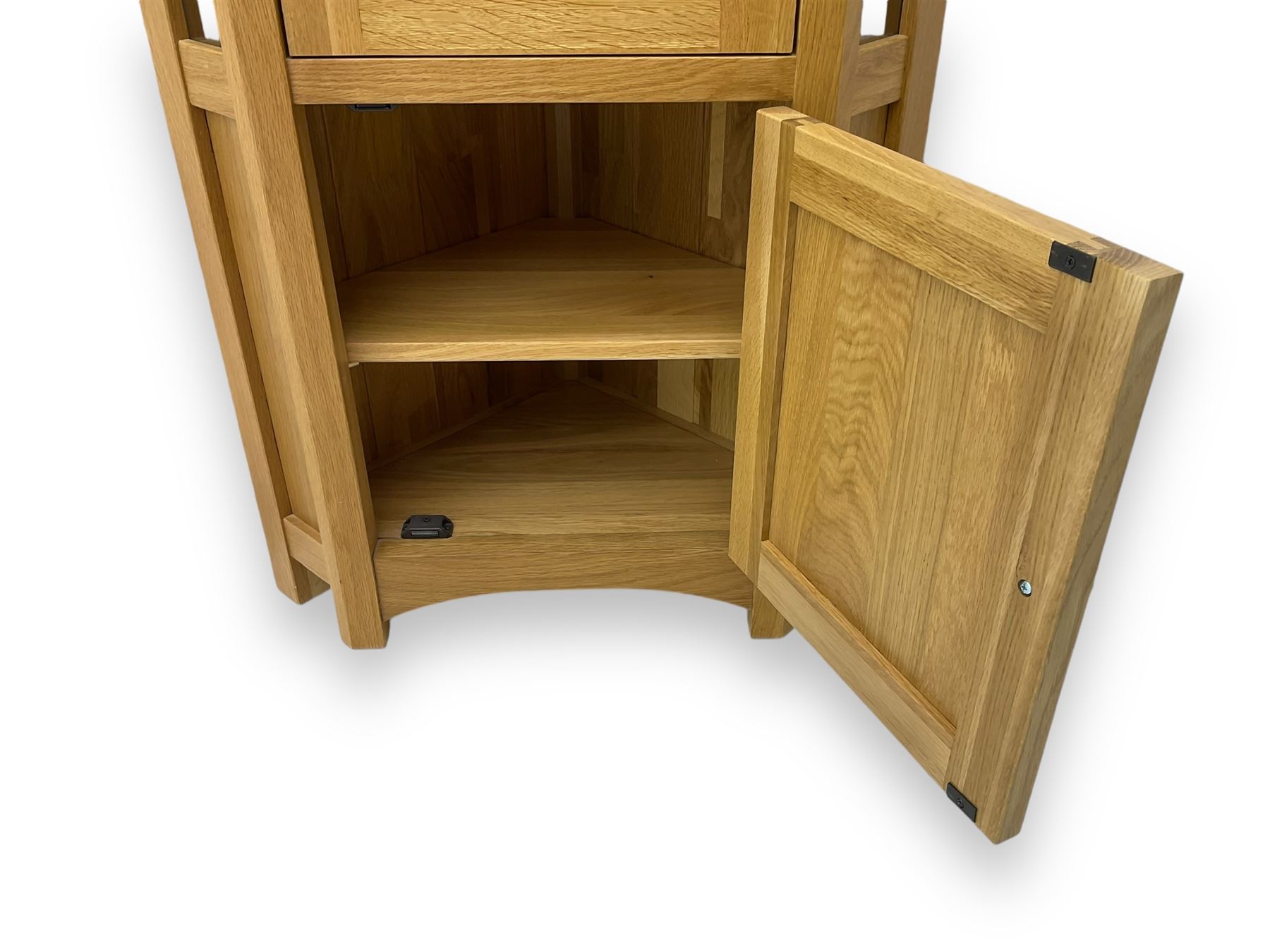 Contemporary light oak corner display cabinet, projecting cornice over single glazed door enclosing three glass shelves, the base fitted with panelled cupboard enclosing single oak shelf, on stile supports