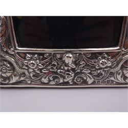 Modern Britannia standard silver mounted photograph frame, of rectangular form with arched top, heavily embossed with figural, palmette, scroll and foliate decoration, with wooden easel style support verso, hallmarked Paul Vernon Fitchie, London 2006, H23.5cm, W15cm