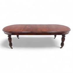 Victorian mahogany extending dining table, rounded rectangular top with moulded edge, pull-out action fitted with two additional leaves, raised on four reeded and fluted baluster legs with brass caps and castors
