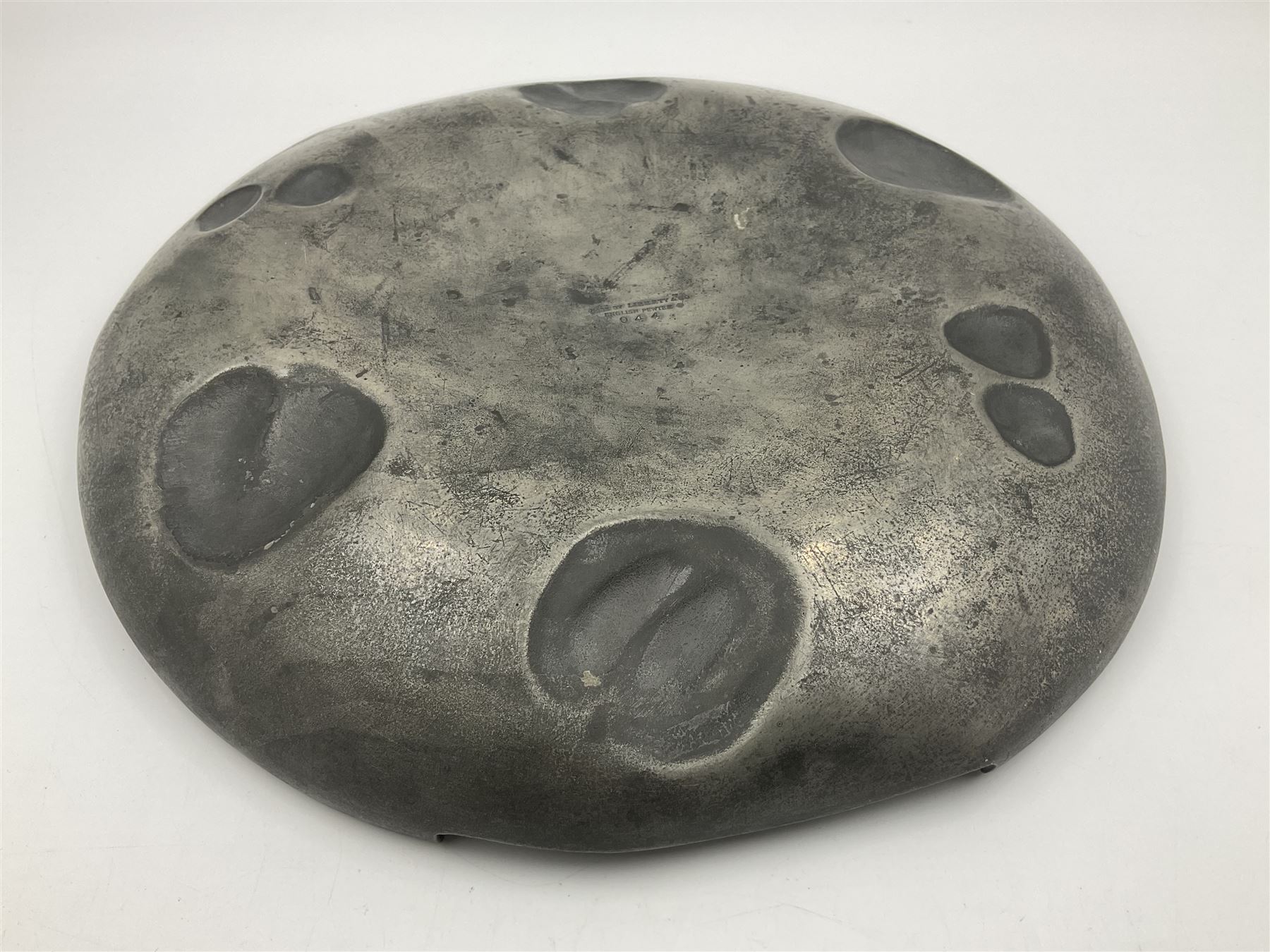 Liberty & Co Tudric pewter Bollelin tray, designed by Archibald Knox, of circular form with shaped edge, cast in relief with foliate tendrils surrounding a green enamel cartouche, impressed beneath Made by Library & Co English Pewter 044, D25.5cm