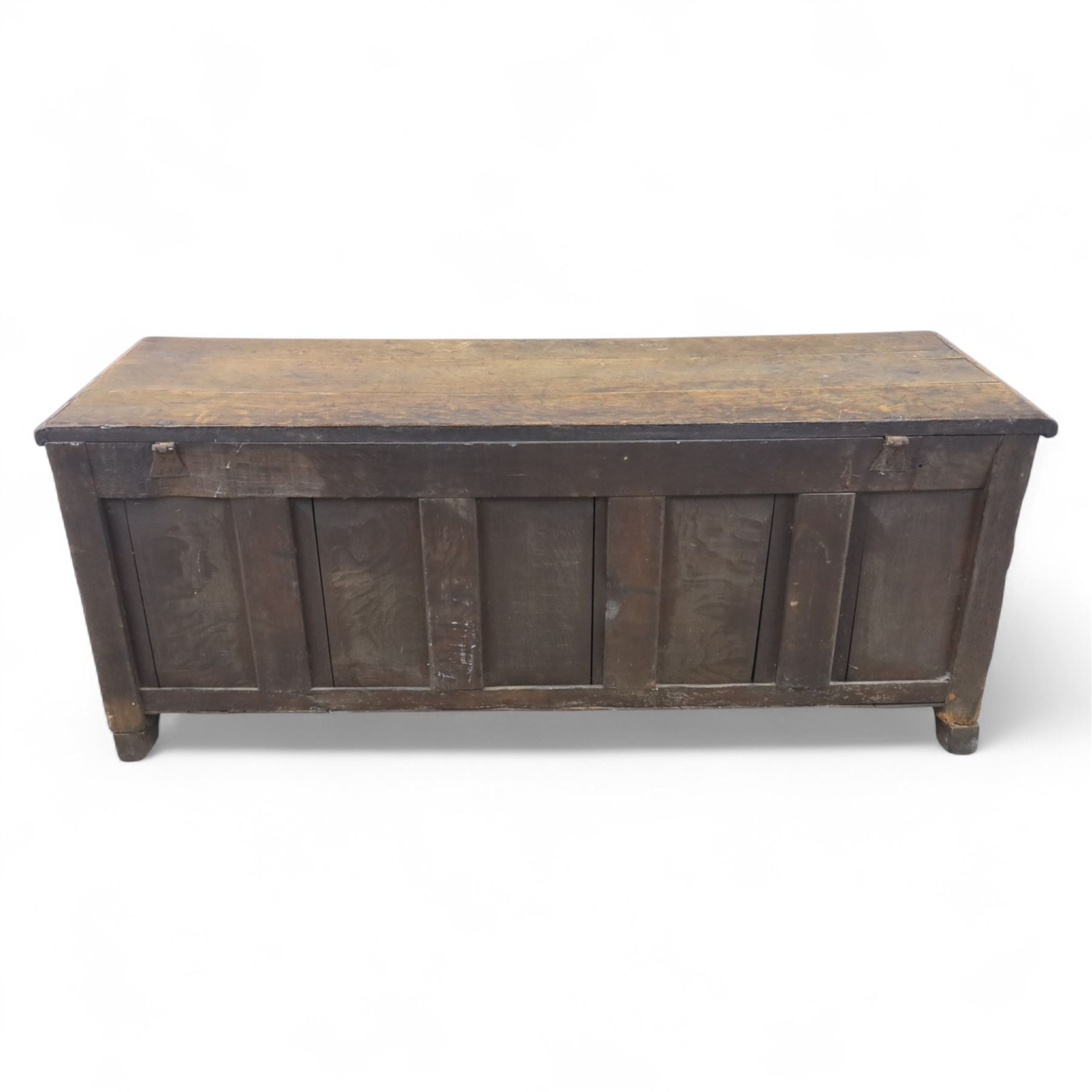 18th century oak five panel chest, with planked top with chamfered edges, hinged top enclosing two candle boxes, five fielded panels flanked by foliate carvings, raised on stile supports
