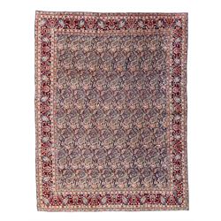 Old Persian Meshed indigo ground carpet, the field profusely decorated with repeating boteh motifs, the crimson border with a trailing stylised plant pattern, guarded by six geometric design bands